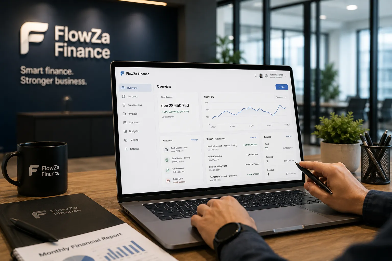 A laptop on a desk showing the FlowZa Finance dashboard — total balance, a cash-flow chart and paid, pending and overdue invoice counts — with one person's hands at the keyboard